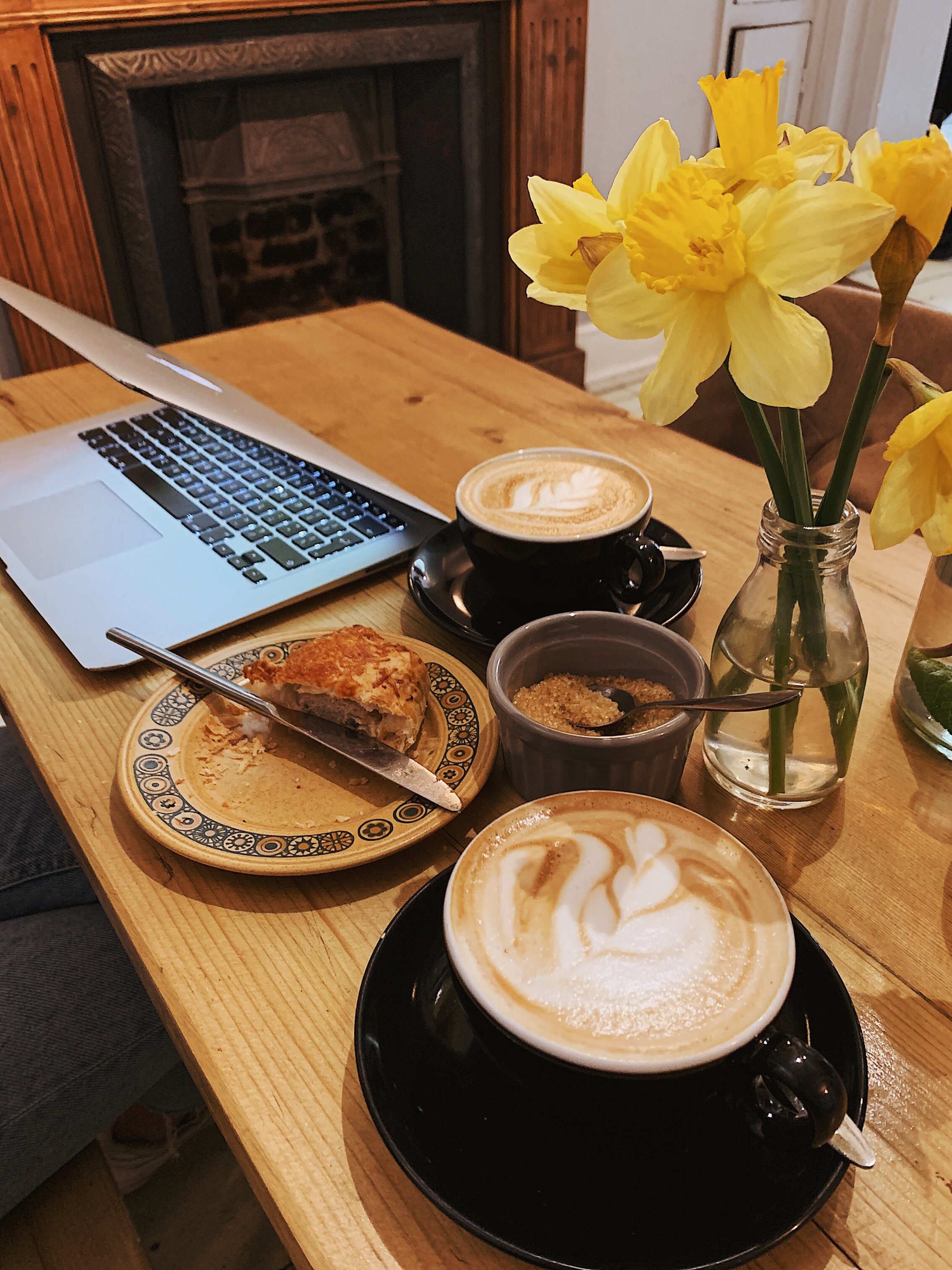 Coffee table with two coffees and a sausage roll